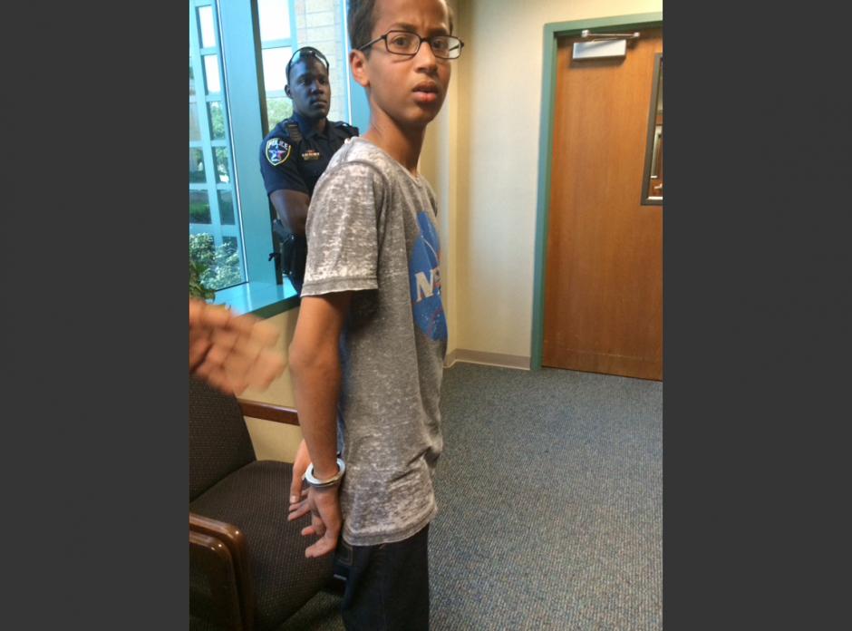 In this Sept. 14, 2015 photo provided by Eyman Mohamed, her brother Ahmed Mohamed stands in handcuffs at Irving police department in Irving, Texas.
