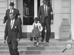 FILE - U.S. Deputy Marshals escort 6-year-old Ruby Bridges from William Frantz Elementary School in New Orleans, in this file photo from November 14, 1960. Bridges has authored a picture book to explain that long-ago experience to the youngest readers. (AP Photo/File)