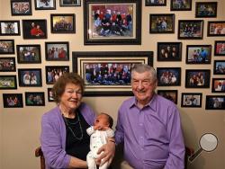 In this April 17, 2015 photo, Leo and Ruth Zanger sit with their 100th grandchild, Jaxton Zanger, in Leo's real estate office in Quincy, Ill. (Phil Carlson/The Quincy Herald-Whig via AP)
