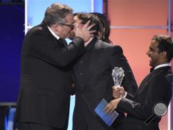 Adam McKay, left, kisses Christian Bale as he accepts the award for best comedy for “The Big Short” at the 21st annual Critics' Choice Awards at the Barker Hangar on Sunday, Jan. 17, 2016, in Santa Monica, Calif. Presenter Aziz Ansari laughs on right (Photo by Chris Pizzello/Invision/AP)