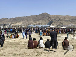 FILE - Hundreds of people gather near a U.S. Air Force C-17 transport plane at the perimeter of the international airport in Kabul, Afghanistan, Aug. 16, 2021. An Afghan couple who arrived in the U.S. as refugees are suing a U.S. Marine and his wife for allegedly abducting their baby. (AP Photo/Shekib Rahmani, File)