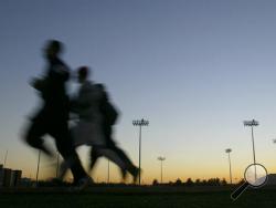 FILE - In this Thursday, Jan. 22, 2004 file photo, students jog around a stadium at sunset in Bowling Green, Ky. A large, international study released on Monday, Oct. 10, 2016, ties heavy exertion while stressed or mad to a tripled risk of having a heart attack within an hour. (Clinton Lewis/Daily News via AP)