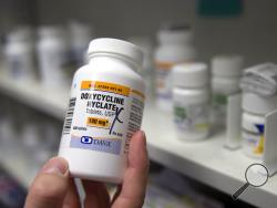 FILE - In this Friday, July 8, 2016 photo, a pharmacist holds a bottle of the antibiotic doxycycline hyclate in Sacramento, Calif. According to a study released on Monday, April 8, 2019, sniffling, coughing kids who were seen via telemedicine visits were far more likely to be prescribed antibiotics than kids who went to a doctor’s office or clinic. (AP Photo/Rich Pedroncelli)