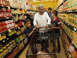 Nadim Fawzi Jouriyeh, a Syrian refugee who arrived in the United States this week with his family, pushes a shopping cart with sons, Farouq Nadim Jouriyeh, left, and Hamzeh Nadim Jouriyeh, Wednesday, 