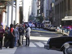Pedestrians stand near Seventh Ave. and 32nd street as police officers work a crime scene Thursday, Sept. 15, 2016, in New York. (AP Photo/Frank Franklin II)