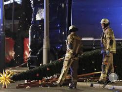 Firefighters look at a toppled Christmas tree after a truck ran into a crowded Christmas market and killed several people in Berlin, Germany, Monday, Dec. 19, 2016. (AP Photo/Michael Sohn)