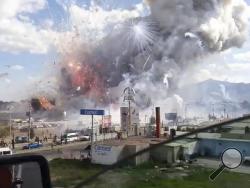 This image made from video recorded from a passing car shows an explosion ripping through the San Pablito fireworks' market in Tultepec, Mexico, Tuesday, Dec. 20, 2016. Sirens wailed and a heavy scent of gunpowder lingered in the air after the afternoon blast at the market, where most of the fireworks stalls were completely leveled. According to the Mexico state prosecutor there are at least 26 dead. (Jose Luis Tolentino via AP)