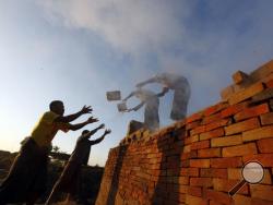In this Friday, Jan. 13, 2017 photo, workers unload bricks at a brick-making factory in Naypyitaw, Myanmar. As bricks continue to be used in construction throughout Myanmar, traditional craftsmen who produce hand-made bricks are facing competition from machine-made bricks which are produced more efficiently. (AP Photo/Aung Shine Oo, File)