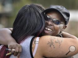 Velma Aiken, the paternal grandmother of Kamiyah Mobley, who was kidnapped as an infant 18 years ago, gets a congratulatory hug from a family member after Mobley was found safe Friday, Jan. 13, 2017, in Jacksonville, Fla. (Will Dickey /The Florida Times-Union via AP)