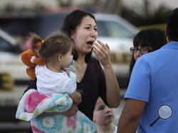 A woman holds her child after San Antonio police helped her and other shoppers exit the Rolling Oaks Mall, Sunday, Jan. 22, 2017, in San Antonio, after a deadly shooting. Authorities say several were injured after a robbery at the shopping mall. (AP Photo/Eric Gay)