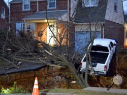A pickup truck dangles over the edge of a sinkhole the swallowed parts of two residential yards Wednesday morning, Jan. 25, 2017, in the Philadelphia suburb of Glenside, Pa. Officials in Cheltenham Township say the hole, which appears to be about 20 feet deep, opened up about 4 a.m. Wednesday. Authorities say nobody's been hurt and there was no obvious, immediate cause for the sinkhole to develop. (Emily Casher Loomis via AP)