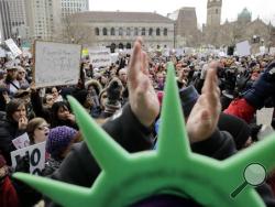 A demonstrator wears a Statue of Liberty hat and applauds during a rally against President Trump's order that restricts travel to the U.S., Sunday, Jan. 29, 2017, in Boston. Trump signed an executive order Friday that bans legal U.S. residents and visa-holders from seven Muslim-majority nations from entering the U.S. for 90 days and puts an indefinite hold on a program resettling Syrian refugees. (AP Photo/Steven Senne)