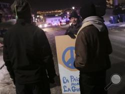 Martin St. Louis holds a sign that reads "la paix pas la guerre" (peace, not war) near a Quebec city mosque after a deadly shooting in Quebec City, Canada, Sunday, Jan. 29, 2017. Quebec Premier Philippe Couillard termed the act "barbaric violence" and expressed solidarity with victims' families. (Francis Vachon/The Canadian Press via AP)