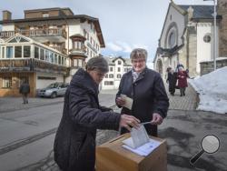 Swiss voters cast their ballot in Obersaxen, Switzerland, Sunday Feb. 12, 2017. Swiss voters were deciding Sunday whether to make it easier for "third-generation foreigners" to get Swiss citizenship and whether to lock in competitive low tax rates for foreign companies in Switzerland. (Benjamin Manser/Keystone via AP)