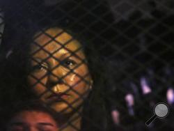 FILE - In this Wednesday, Feb. 8, 2017, file photo, Guadalupe Garcia de Rayos is locked in a van that is stopped in the street by protesters outside the Immigration and Customs Enforcement facility in Phoenix. Advocacy groups said that Immigration and Customs Enforcement officers are rounding up people in large numbers around the country as part of stepped-up enforcement under President Donald Trump. The government said it's simply enforcing the laws and taking dangerous immigrants off the streets. On Wedne