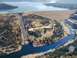 This June 23, 2005, aerial photo provided by the California Department of Water Resources shows Oroville Dam, Lake Oroville and the Feather River in the foothills of Sierra Nevada near Oroville, Calif. The concrete spillway that was undermined and developed huge holes in the last few days is at lower left. Release of water from the dam, the damaged spillway and the use of an earthen emergency spillway has caused a temporary evacuation on Sunday, Feb. 12, 2017, of thousands of people downstream. (Paul Hames/