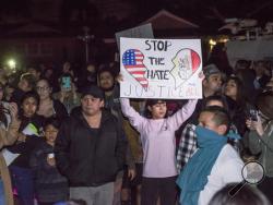 Protesters hold signs in front of an LAPD officer's home in Anaheim, Calif., Wednesday, Feb. 22, 2017. A Los Angeles policeman is under investigation after a video appears to show him firing a single round during an off-duty tussle with a 13-year-old boy. No one was injured but two teenagers were arrested after the incident, which spurred dozens of people to protest against police Wednesday night in the streets of Anaheim, where the officer lives and the confrontation occurred. (Joshua Sudock/The Orange Cou