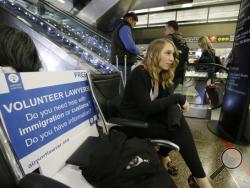 Asti Gallina, a volunteer law student from the University of Washington, sits at a station near where passengers arrive on international flights at Seattle-Tacoma International Airport, Tuesday, Feb. 28, 2017, in Seattle. Gallina was volunteering with the group Airport Lawyer, which also offers a secure website and mobile phone app that alerts volunteer lawyers to ensure travelers make it through customs without trouble. Airport officials and civil rights lawyers around the country are getting ready for Pre