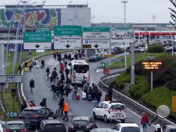 Travellers walk on the highway to the Orly airport, south of Paris, Saturday, March, 18, 2017. A man was shot to death Saturday after trying to seize the weapon of a soldier guarding Paris' Orly Airport, prompting a partial evacuation of the terminal, police said. (AP Photo/Thibault Camus)