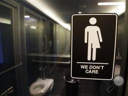 FILE - This Thursday, May 12, 2016, file photo, shows a sign outside a restroom at 21c Museum Hotel in Durham, N.C. The Associated Press has determined that North Carolina's law limiting LGBT protections will cost the state more than $3 billion in lost business over a dozen years.That's despite Republican assurances that the "bathroom bill" isn't hurting the economy. (AP Photo/Gerry Broome, File)