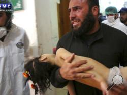 This photo provided on Tuesday April 4, 2017, by the Syrian anti-government activist group Edlib Media Center, that is consistent with independent AP reporting, shows a man carrying a child following a suspected chemical attack, at a makeshift hospital in the town of Khan Sheikhoun, northern Idlib province, Syria. The suspected chemical attack killed dozens of people on Tuesday, Syrian opposition activists said, describing the attack as among the worst in the country's six-year civil war. (Edlib Media Cente