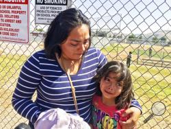 Elizabeth Barajas hugs her daughter, Marissa Perez, 9, following their reunion as Marissa recounted her experiences being in the classroom in which her teacher was shot to death at North Park Elementary School in San Bernardino, Calif., Monday, April 10, 2017. (AP Photo/Christopher Weber)