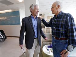 In this photo taken March 29, 2017, Dr. David Maloney of the Fred Hutchinson Cancer Research Center is greeted by patient Ken Shefveland, whose lymphoma was successfully treated with CAR-T cell therapy. Immune therapy is the hottest trend in cancer care and its next frontier is creating "living drugs" that grow inside the body into an army that seeks and destroys tumors. (AP Photo/Elaine Thompson)