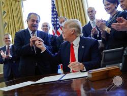 FILE - In this Feb. 24, 2017, file photo, President Donald Trump gives the pen he used to sign an executive order to Dow Chemical President, Chairman and CEO Andrew Liveris, as other business leaders applaud in the Oval Office of the White House in Washington. Dow Chemical is pushing the Trump administration to scrap the findings of federal scientists who point to a family of widely used pesticides as harmful to about 1,800 critically threatened or endangered species. Liveris is a close adviser to President
