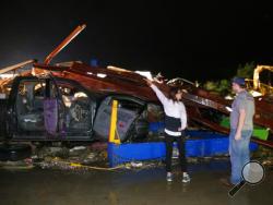 Ernestine Cook of Canton, Texas, points out the damage to spotter Michael Search of Henderson, Texas, as they inspect the damage done to the I-20 Dodge dealership after a tornado hit Canton, Texas, Saturday, April 29, 2017. Cars and trucks were piled high and the service area was destroyed. (Tom Fox/The Dallas Morning News via AP)