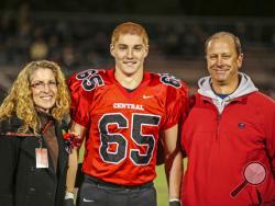 This Oct. 31, 2014, photo provided by Patrick Carns shows Timothy Piazza, center, with his parents Evelyn Piazza, left, and James Piazza, right, during Hunterdon Central Regional High School football's "Senior Night" at the high school's stadium in Flemington, N.J. Prosecutors in Pennsylvania are set to announce, Friday, May 5, 2017, the results of a grand jury investigation into the death of the Penn State student, Timothy Piazza, who fell down steps Feb. 4, during an alcohol-fueled pledge ceremony. (Patri