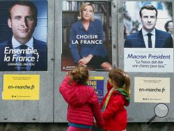 Children walk past election campaign posters for French centrist presidential candidate Emmanuel Macron and far-right candidate Marine Le Pen, in Osses, southwestern France, Friday May 5, 2017. France will vote on Sunday May 7 in the second round of the presidential election. (AP Photo/Bob Edme)