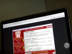 FILE - In this May 13, 2017 file photo, a screenshot of the warning screen from a purported ransomware attack, as captured by a computer user in Taiwan, is seen on laptop in Beijing. (AP Photo/Mark Schiefelbein, File)