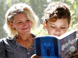  Theo Galkin, 8, rereads a favorite part of "Harry Potter and the Sorcerer's Stone" while posing for a picture with his mother Chloe Galkin at their home in South Orange, N.J., Wednesday, June 28, 2017. As the 20th anniversary of the initial publishing of the first Harry Potter book is celebrated this week, another generation is being introduced to Harry, Hogwarts and all the rest of the magical world created by author J.K. Rowling. (AP Photo/Seth Wenig)
