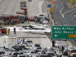  Emergency responders gather round the crash of a Cessna 310 aircraft on Interstate 405, just short of a runway at John Wayne Airport in Costa Mesa, Calif., Friday, June 30, 2017. Two people were injured in the small plane crash. (AP Photo/Chris Carlson)