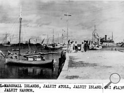 This undated photo discovered in the U.S. National Archives by Les Kinney shows people on a dock in Jaluit Atoll, Marshall Islands. A new documentary film proposes that this image shows aviator Amelia Earhart, seated third from right, gazing at what may be her crippled aircraft loaded on a barge. (Office of Naval Intelligence/U.S. National Archives via AP)