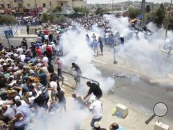 Palestinians run away from tear gas thrown by Israeli police officers outside Jerusalem's Old City, Friday, July 21, 2017. Israel police severely restricted Muslim access to a contested shrine in Jerusalem's Old City on Friday to prevent protests over the installation of metal detectors at the holy site. (AP Photo/Mahmoud Illean)