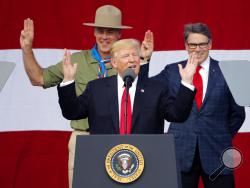 President Donald Trump, front left, gestures as former boys scouts, Interior Secretary Ryan Zinke, left, Energy Secretary Rick Perry, watch at the 2017 National Boy Scout Jamboree at the Summit in Glen Jean,W. Va., Monday, July 24, 2017. (AP Photo/Steve Helber)