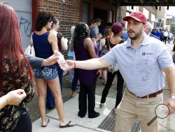 Gabe Perlow, chief executive officer of PurePenn, right, hands out water to people lined up in downtown McKeesport, Pa., to attend a Medical Marijuana Job Fair, Thursday, July 27, 2017. Named as one of Pennsylvania's first grower-processor licensees for medicinal cannabis, PurePenn, based in McKeesport, Pa., will hire in the next ten months up to 50 full-time employees including: sales managers, cultivation managers, cultivators, packagers and lab supervisors. (AP Photo/Gene J. Puskar)