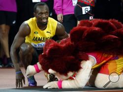 Jamaica's Usain Bolt smiles next to mascot Hero the Hedgehog after his men's 100m heat the World Athletics Championships in London Friday, Aug. 4, 2017. (AP Photo/Matthias Schrader)