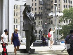 FILE- In this Aug. 10, 2016 file photo, people walk by a statue of late Philadelphia Mayor Frank Rizzo, who also served as the city's police commissioner, on Thomas Paine Plaza outside the Municipal Services Building in Philadelphia. A city councilwoman is leading the push to take down the likeness of Rizzo, considered by some as a tough-talking, tougher-on-crime lawmaker, but to others as a racist, anti-gay bigot. (AP Photo/Dake Kang, File)