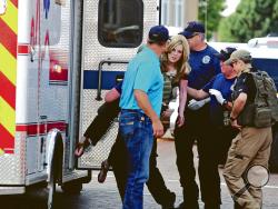 An injured woman is carried to an ambulance in Clovis, N.M., Monday, Aug. 28, 2017, as authorities respond to reports of a shooting inside a public library. A city official says police have taken a person into custody who they believe is responsible for a shooting at the library. (Tony Bullocks/The Eastern New Mexico News via AP)