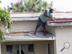 A homeowner makes last minute repairs to his roof in preparation for Hurricane Irma, in St. John's, Antigua and Barbuda, Tuesday, Sept. 5, 2017. Irma grew into a dangerous Category 5 storm, the most powerful seen in the Atlantic in over a decade, and roared toward islands in the northeast Caribbean Tuesday on a path that could eventually take it to the United States. (AP Photo/Johnny Jno-Baptiste)