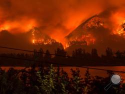 FILE--This Monday, Sept. 4, 2017, file photo provided by KATU-TV shows a wildfire as seen from near Stevenson Wash., across the Columbia River, burning in the Columbia River Gorge above Cascade Locks, Ore. The fast-moving wildfire chewing through Oregon's Columbia River Gorge is threatening more than homes and people. It's also devouring the heart of the state's nature-loving identity. (Tristan Fortsch/KATU-TV via AP, file)