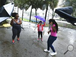 Umbrellas held by Janesse Brown, left, and her daughter Briana Johnson, 12, right, get torn apart by strong winds as Kyra Johnson, 8 watch, while they tried to visit Southbank Riverwalk in Jacksonville, Fla., Sunday, Sept. 10, 2017, as Hurricane Irma passes the area. (Bob Self/The Florida Times-Union via AP)