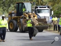Workers with Carroll & Carroll Inc. clean debris from residents' yards along Lewis Avenue on Tybee Island on Wednesday, Sept. 13, 2017. Storm surge flooded hundreds of homes near beaches and marshes, sunk numerous boats and trashed docks on the Georgia coast even though Irma was a weakened tropical storm when its center crossed the state more than 100 miles (160 kilometers) inland. (Dash Coleman/Savannah Morning News via AP)