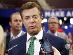 FILE - In this July 17, 2016 file photo, then-Trump Campaign Chairman Paul Manafort talks to reporters on the floor of the Republican National Convention at Quicken Loans Arena in Cleveland as Rick Gates listens at back left. Manafort, said during the presidential race that he was willing to provide “private briefings” for a Russian billionaire the U.S. government considers close to Russian President Vladimir Putin. That’s according to a July 2016 email exchange Manafort wrote to a former employee of his po