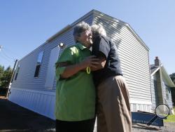 FILE - In this Aug. 23, 2016, file photo, Mayor Andrea "Andy" Pendleton, right, hugs resident Linda Bennett in front of Bennett's new FEMA trailer installed in front of her flood ravaged home in Rainelle, W. Va. Just before Hurricane Harvey made landfall in Texas in August 2017 as a Category 4 hurricane and in the floods that ensued, the federal government was auctioning off used disaster-response trailers at fire-sale prices. (AP Photo/Steve Helber, File)