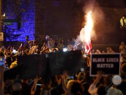 A flag is set on fire as protesters gather, Friday, Sept. 15, 2017, in St. Louis, after a judge found a white former St. Louis police officer, Jason Stockley, not guilty of first-degree murder in the death of a black man, Anthony Lamar Smith, who was fatally shot following a high-speed chase in 2011. (AP Photo/Jeff Roberson)
