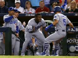 Los Angeles Dodgers' Austin Barnes (15) celebrates with Yasiel Puig in the dugout after hitting a solo home run during the sixth inning of game 3 of baseball's National League Division Series against the Arizona Diamondbacks, Monday, Oct. 9, 2017, in Phoenix. (AP Photo/Rick Scuteri)
