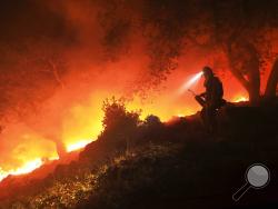 A San Diego Cal Fire firefighter monitors a flare up on a the head of a wildfire (the Southern LNU Complex), off of High Road above the Sonoma Valley, Wednesday Oct. 11, 2017, in Sonoma, Calif. A wind shift caused flames to move quickly up hill and threaten homes in the area. Three days after the fires began, firefighters were still unable to gain control of the blazes that had turned entire Northern California neighborhoods to ash and destroyed thousands of homes and businesses. (Kent Porter/The Press Demo